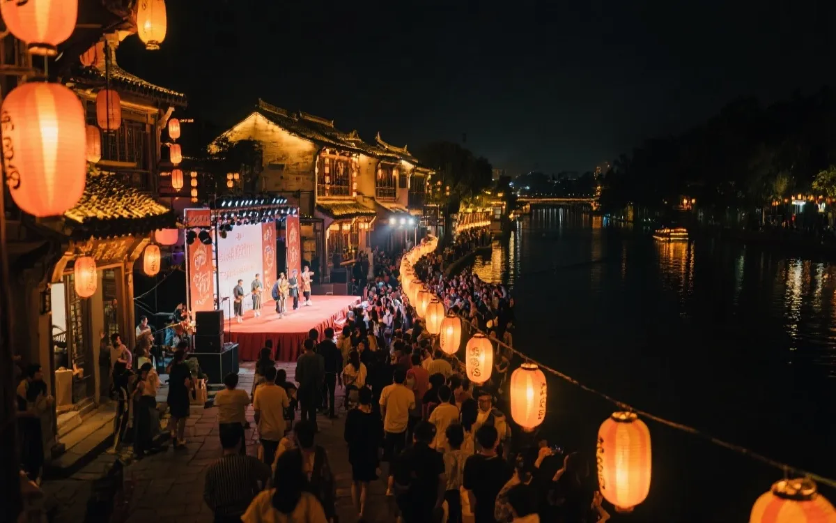 夜幕下的三国联合主办文化展演，灯火与舞台交相辉映，观众在水岸与街市间流动